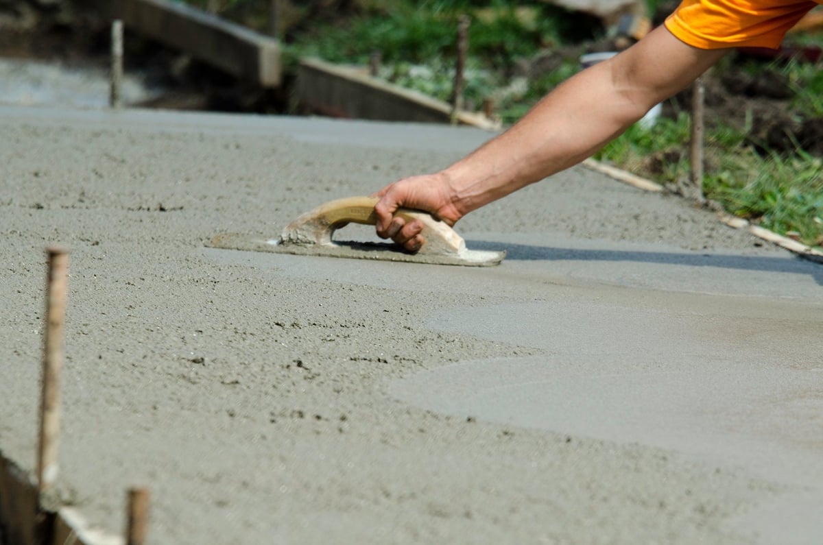 Craftsman smoothing fresh concrete with a hand trowel