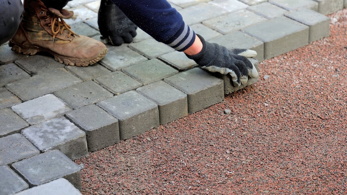 Construction worker laying concrete pavers on a Phoenix driveway